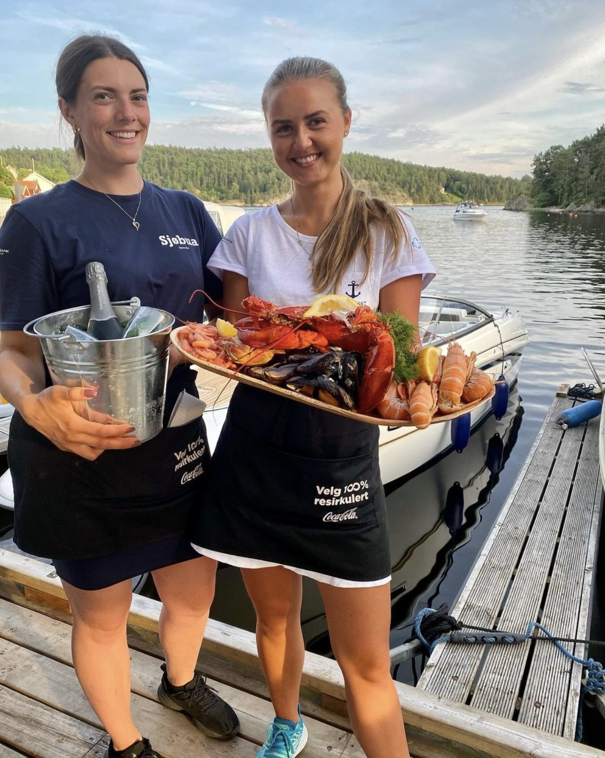 To smilende servitører serverer luksuriøst skalldyrfat med hummer, reker og blåskjell på brygga – premium sjømatopplevelse ved Ringdalsfjorden i Sponvika