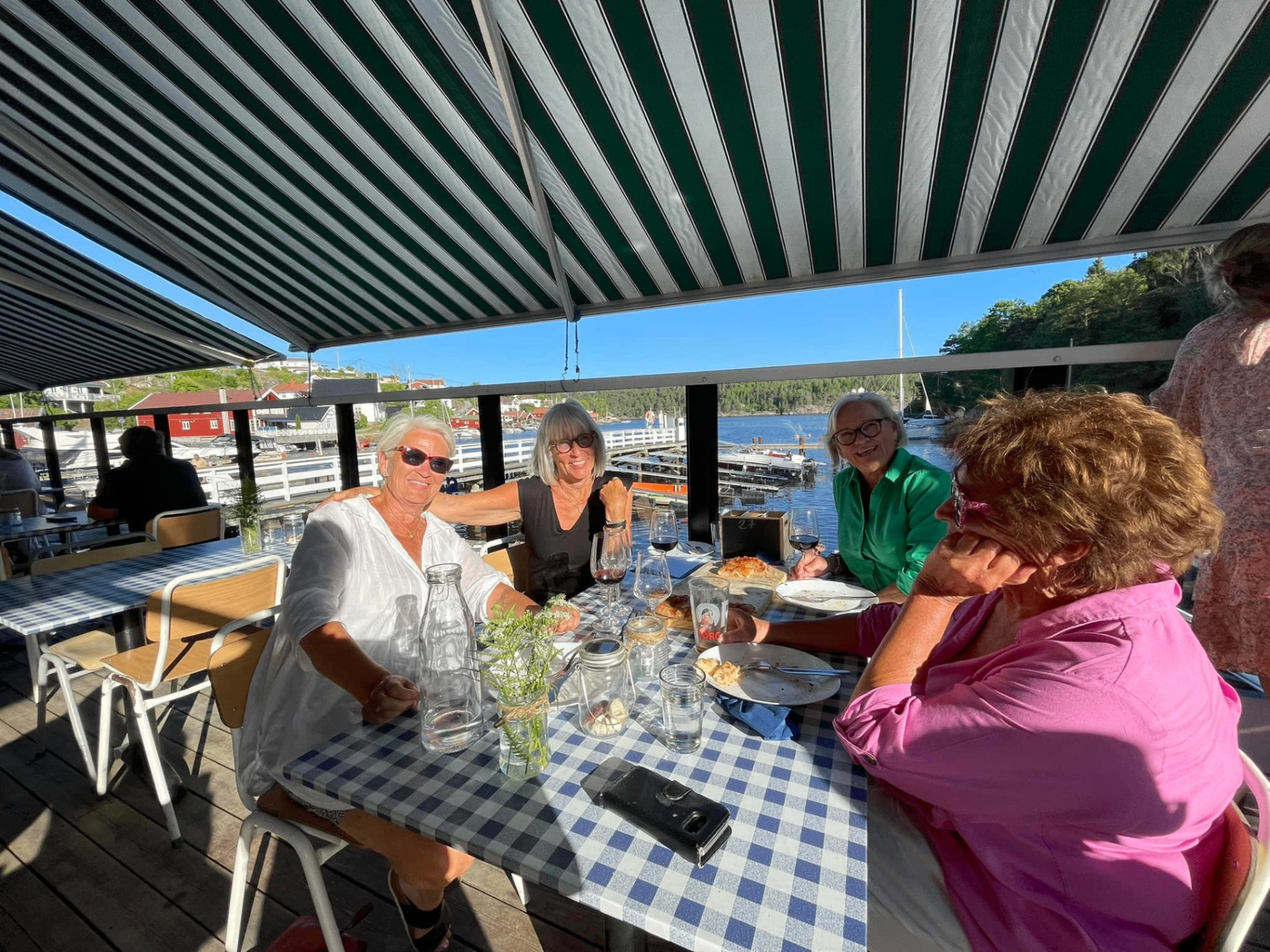 Vennegjente koselig seg med mat og vin på Sjøbuas terrasse med utsikt over Ringdalsfjorden – sosialt og hyggelig ved bryggekanten i Sponvika